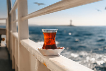 Glass of turkish tea on the ferry (vapur), Bosphorus view in Istanbul, warm colours