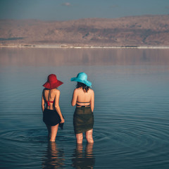 Woman swimming in Israel dead sea in red swimsuit and red hat. Perfectly blue water and sky. Summer scenic picture with copy space