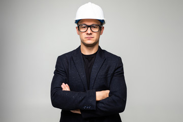 Confident man engineer wearing protective helmet holding hands crossed looking away isolated over white background.