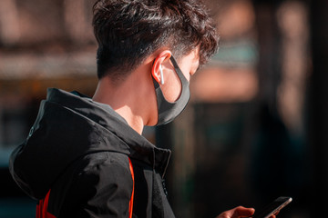  Asian young man wearing surgical face mask to prevent flu disease Corona virus and PM 2.5 dust and pollution. Hong Kong student in a safe zone 