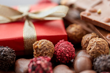 sweets concept - close up of handmade chocolate candies and red gift box