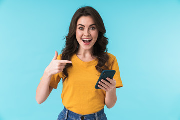 Surprised young girl using mobile phone pointing.