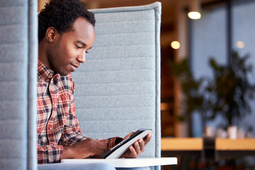 Businessman At Desk In Cubicle In Modern Office Work Space Using Digital Tablet