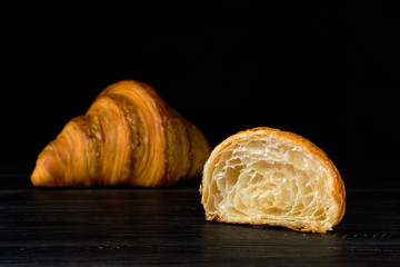 Fresh golden croissant on black table