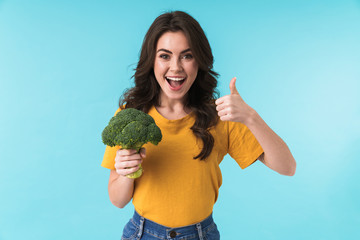 Positive young beautiful woman holding broccoli.
