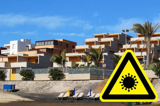 Corona virus concept with warning sign and holiday apartments at beach in background (digital composite)
