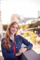 Portrait Of Smiling Young Businesswoman Standing Outside Office Building With City Skyline Behind