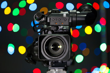 Modern video camera against blurred colorful lights