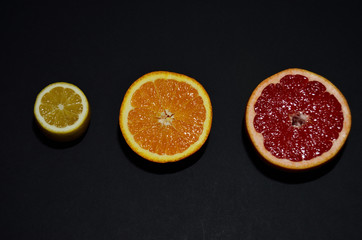 Fototapeta na wymiar red grapefruit orange yellow lemon on a black background top view horizontal orientation
