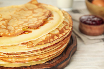 Fresh thin pancakes on white wooden table, closeup