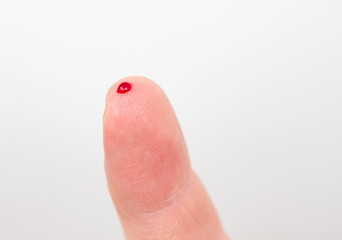 Fingertip with small drop of blood. 