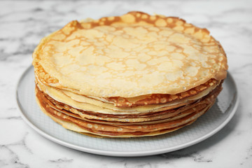 Stack of fresh thin pancakes on white marble table