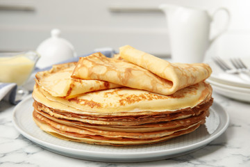 Stack of fresh thin pancakes on white marble table