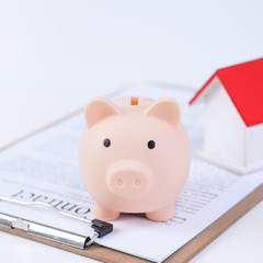Financial concpet - Piggy bank, beautiful red white wooden house model on white background, saving money to buy insurance, close up, copy space.