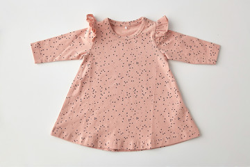 clothes, babyhood and clothing concept - pink dress for baby girl with dot print on white background