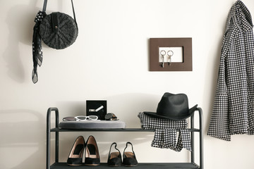 Black shelving unit with shoes and different accessories near white wall