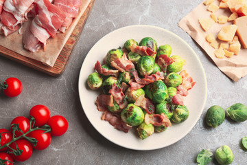 Delicious Brussels sprouts with bacon on marble table, flat lay