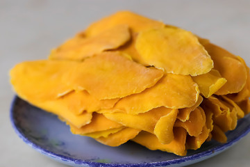Sun-dried mango slices on a blue plate close-up.