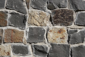 Decorative wall of artificial torn stone in brown tones. Stone masonry in geometric pattern as background or texture.