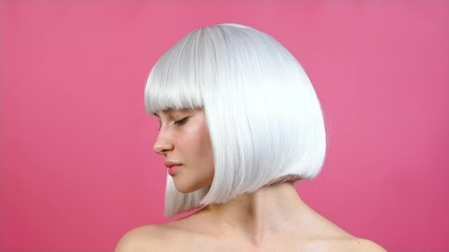 young glamorous blonde girl in a bob wig touches the tips of her hair, straightens her hair, posing closeup, looking at the camera. studio portrait without makeup. beauty salon concept