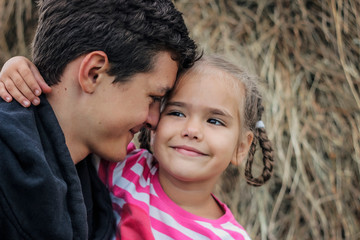 Fototapeta premium Young teenager hugging his smaller adorable sister during their summer walking in the meadow