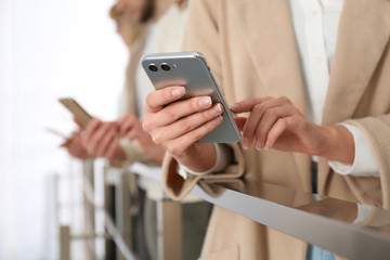 Young woman using modern smartphone indoors, closeup