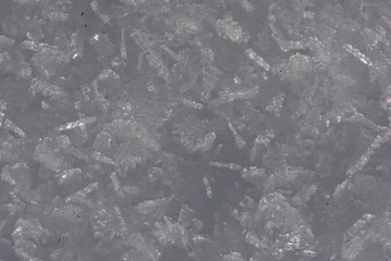 Close up sunlit ice carpet from sparkling and flaring sharp large crystals of snow and ice