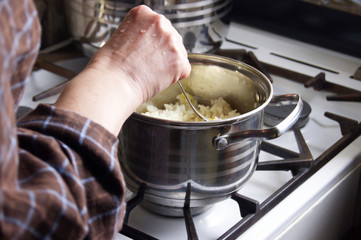 A woman is standing at the stove. Prepares homemade food.
