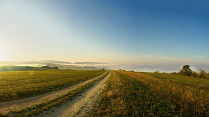 Fototapeta na wymiar Povazsky Inovec Hill in Slovakia in the valley on sunrise. Landscape photo of field with green grass, fog and beautiful sun rays. Perfect view point from meadow on sunrise. Slovakia landscape.