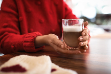 Woman with fresh aromatic coffee at table in cafe, closeup