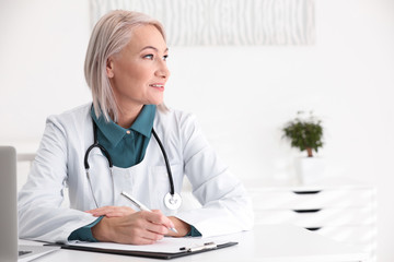 Mature female doctor in white coat at workplace