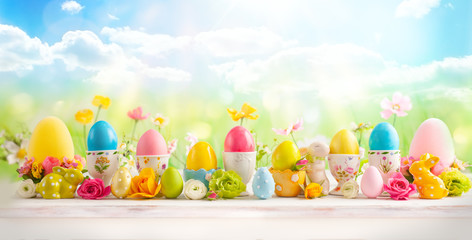 Easter concept with colorful decorated eggs in egg cups and flowers