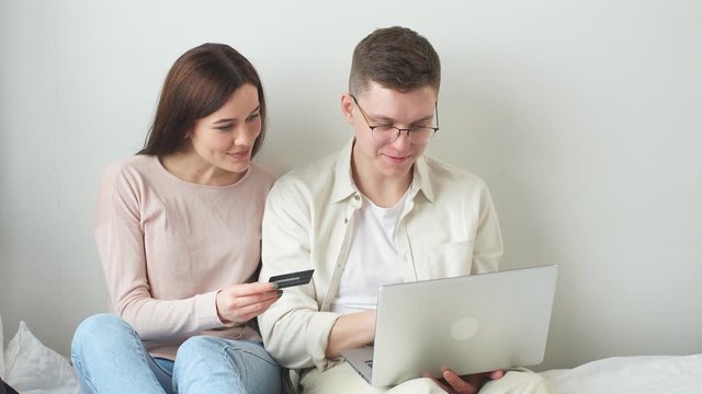 Young man and his beautiful wife using credit card to buy goods, ordering pizza, sushy, sushi, sale, bargain, delivery service.