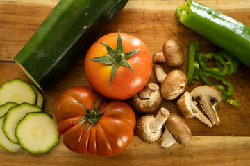 Hortalizas, tomate calabacín champiñones pimiento en fondo de madera slowfood comida de proximidad