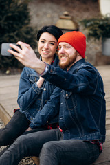 Young stylish couple in love takes a selfie outdoors