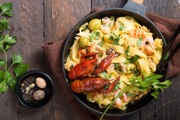 Seafood fettuccine pasta with crayfishes, octopus shrimps, on stone pan. Gourmet dish