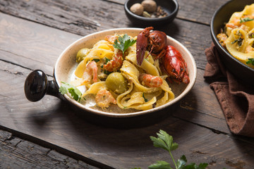 Seafood fettuccine pasta with crayfishes, octopus shrimps, on stone pan. Gourmet dish
