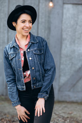 Portrait of an amazing young smiling girl in a hat and denim jacket, outdoors