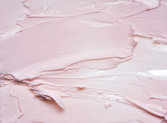 Gently pink brush strokes and texture of face cream or pink acrylic paint on a white background