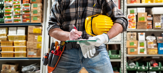 Electrician in the electrical components store writes on the notebook. Construction industry,...