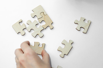 Girl's hands begin to collect empty wooden puzzle pieces