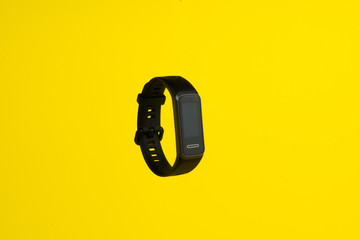 Front side of the black smart watch on yellow background. - Powered by Adobe