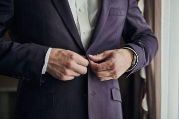 Businessman wears a jacket,male hands closeup,groom getting ready in the morning before wedding ceremony