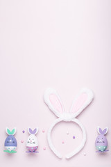 Funny cute bunny eggs and bunny rabbit ears for kids on pastel pink table top, Easter holiday concept. Easter decoration for kids flat lay, copy space
