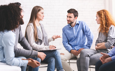 People sitting in circle and listening mentor during group therapy session