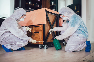 Specialists in protective suits do disinfection or pest control in the apartment.