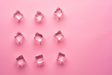 Ice cubes on pink background. Flat lay