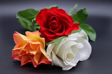 bouquet of red, white and orange roses on black background