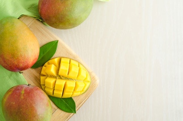 flat lay ripe juicy exotic mango on white and green background. slice and whole fruit on wooden...