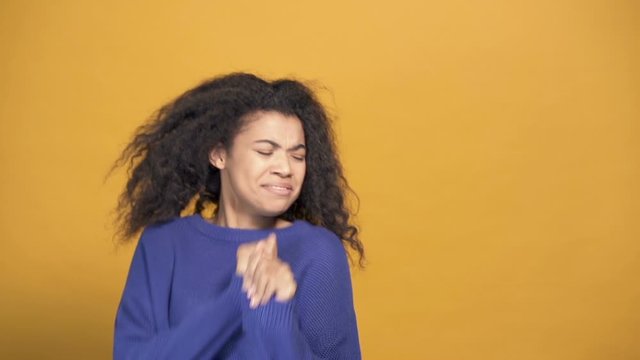 Young afro ameican woman rejoicing and dancing. Yellow background. Slowmotion.